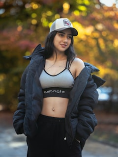 A woman poses with a jacket and cap.