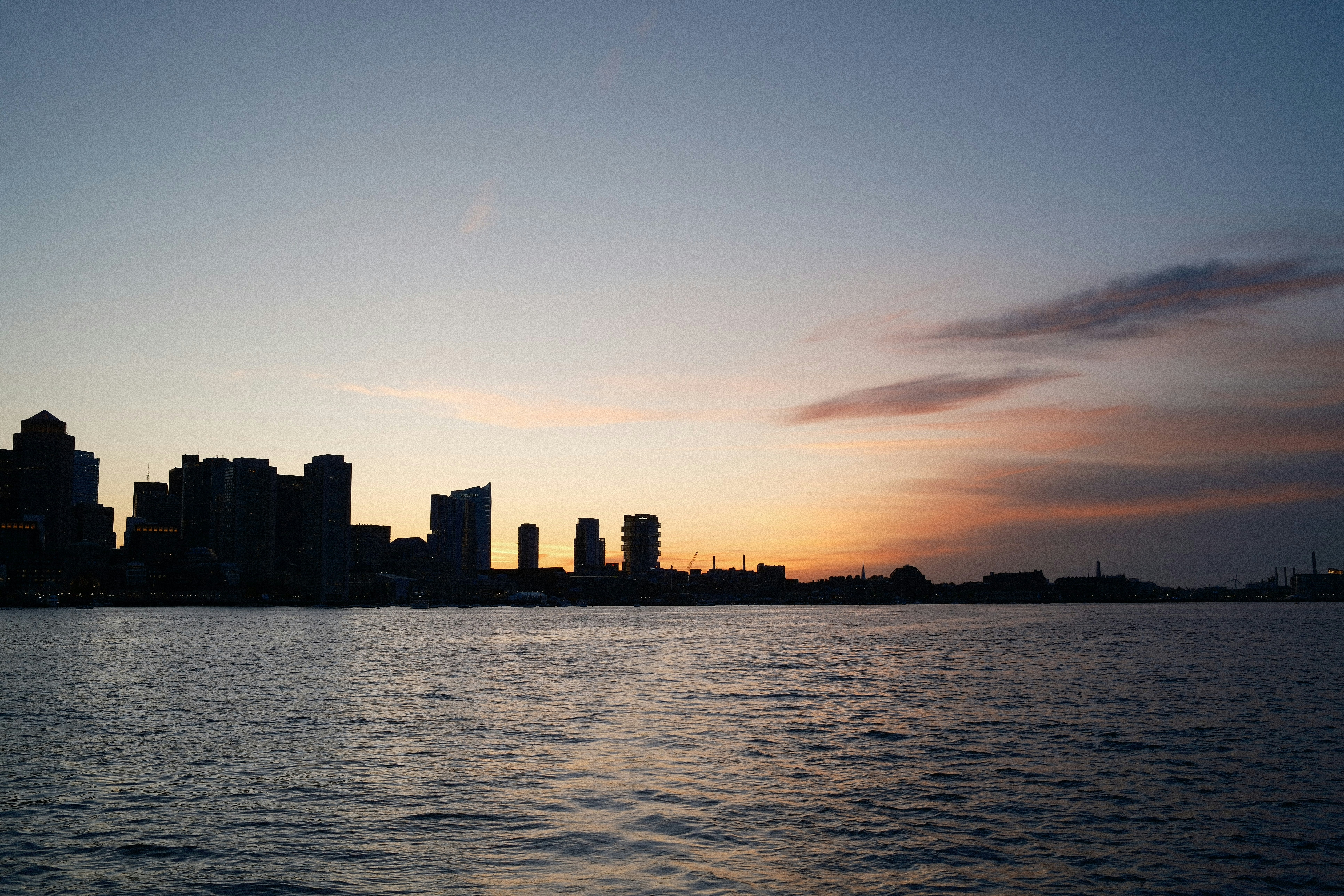 Silhouette of a city skyline at sunset over water.