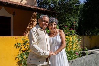 Happy elderly couple smiling outside their home.