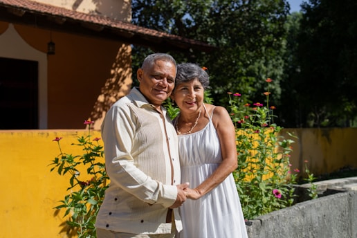 Happy elderly couple smiling outside their home.