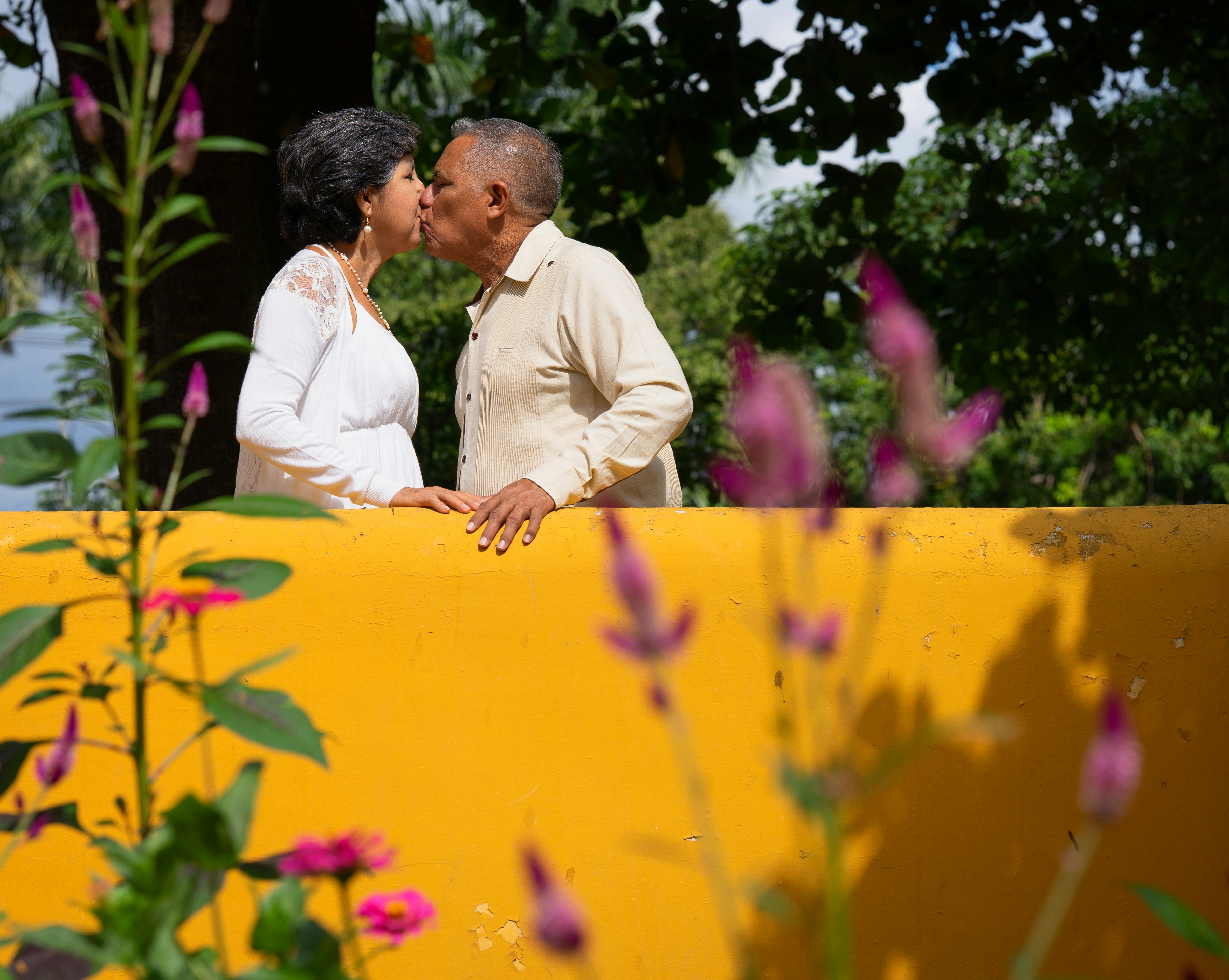 An elderly couple shares a loving kiss.