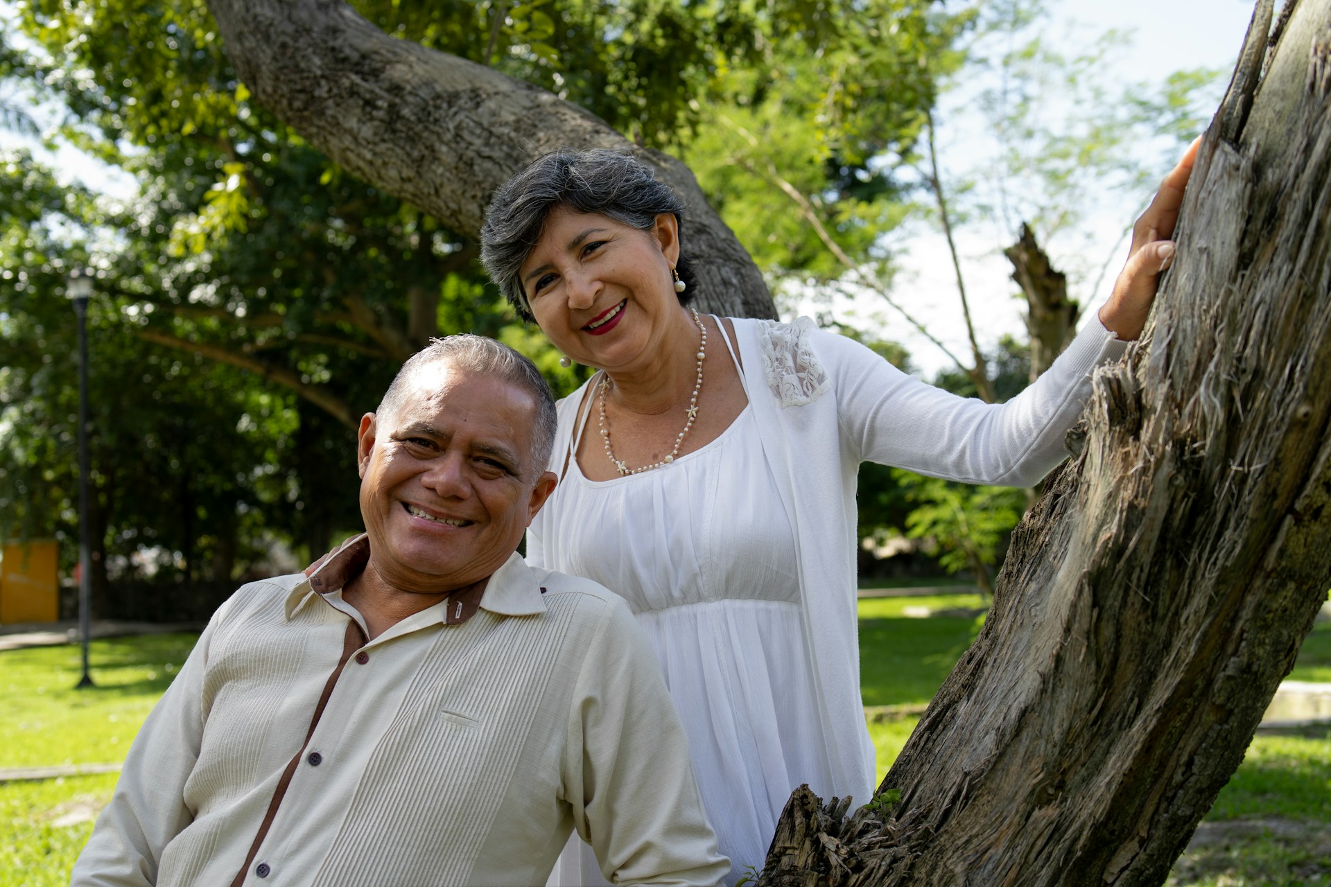 Smiling couple poses near a tree outdoors.