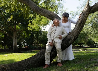 An elderly couple poses under a tree.