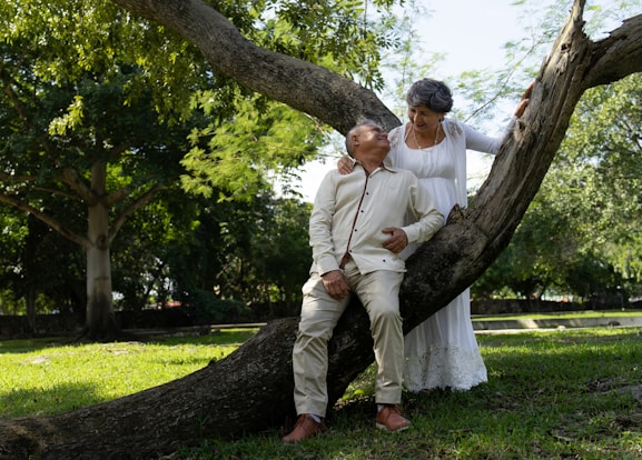 An elderly couple poses under a tree.