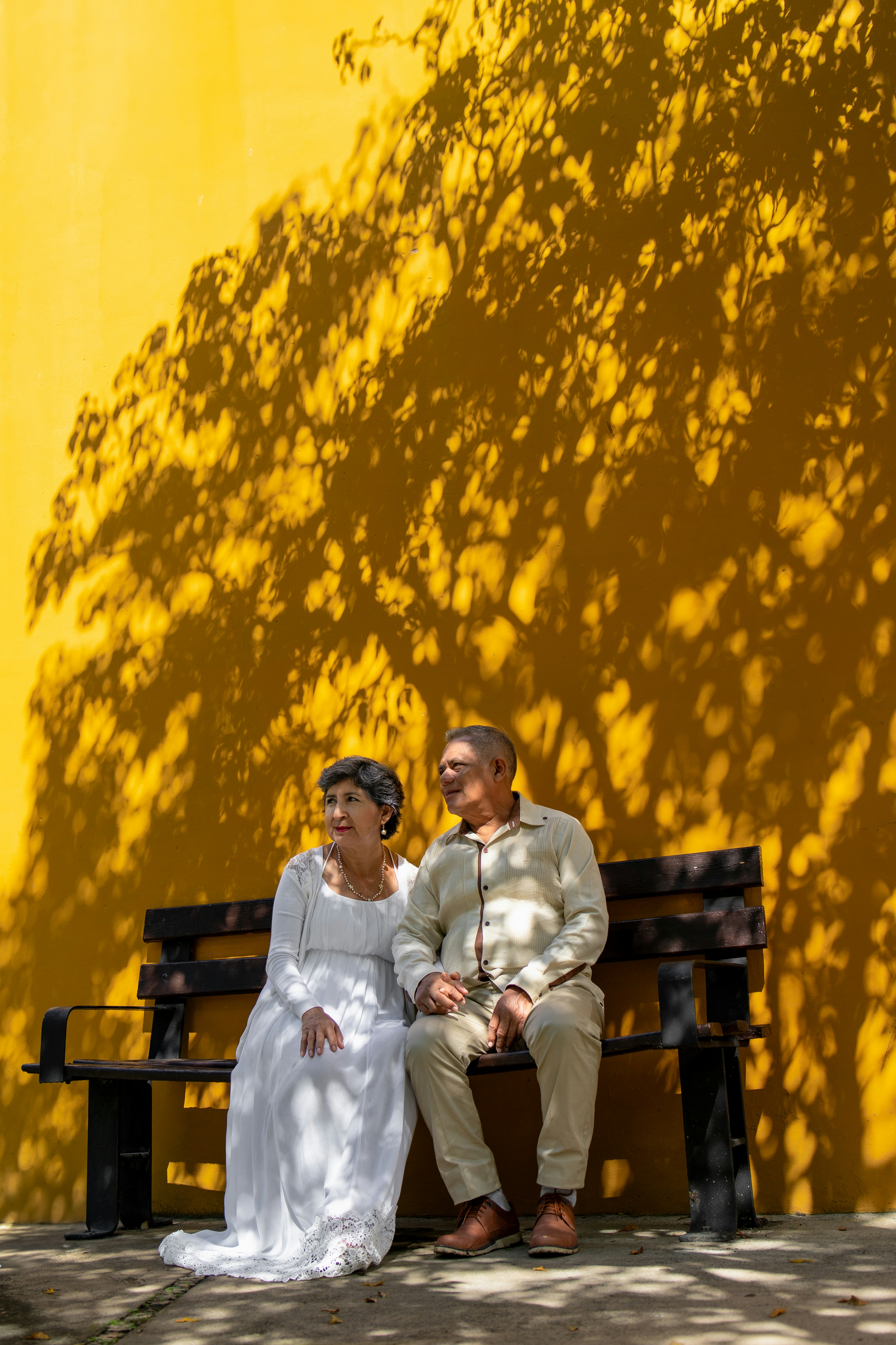 An elderly couple sits on a bench.