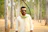 A man poses in a forest.