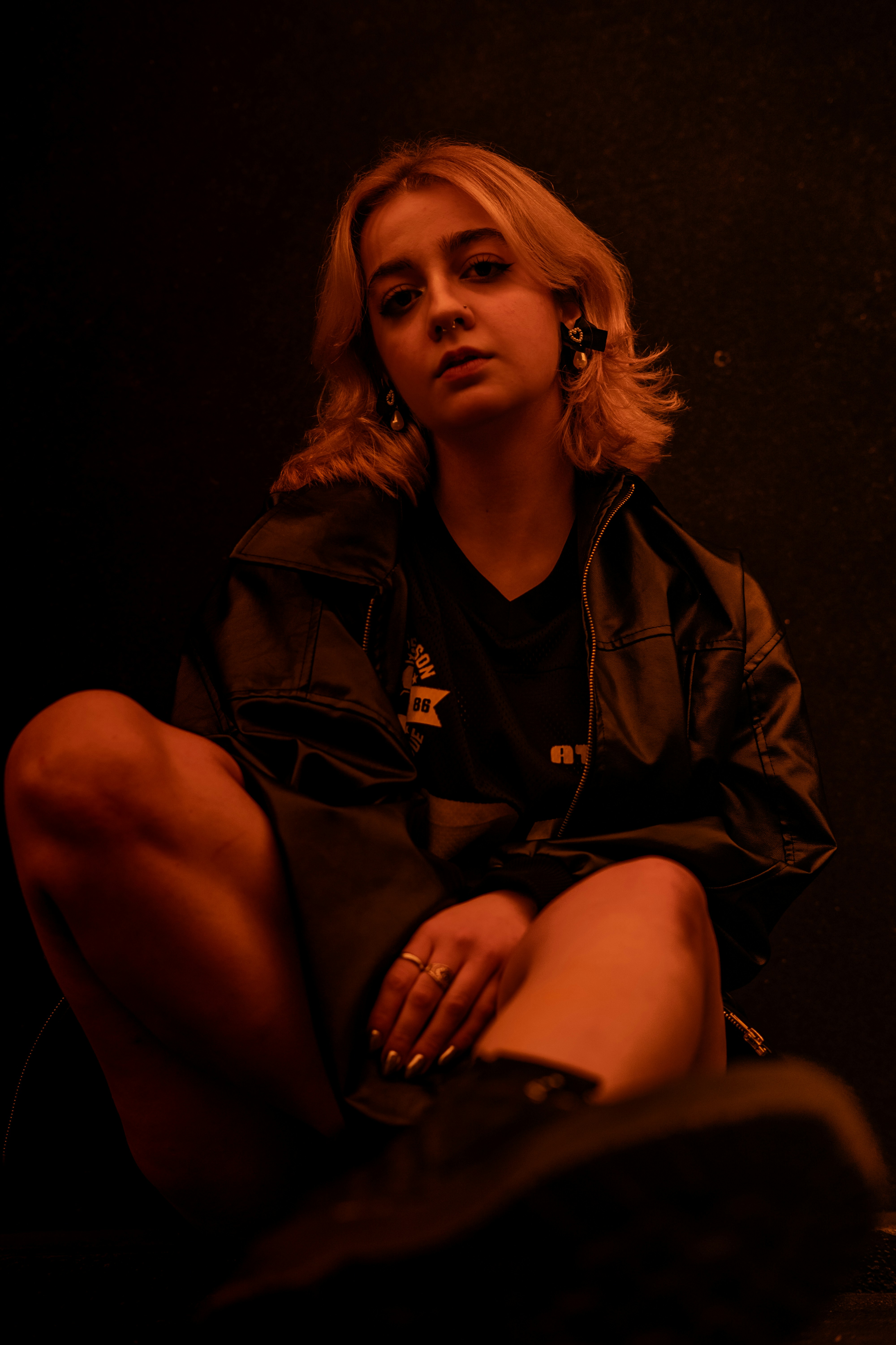 A woman is sitting in a dark, red-lit room.