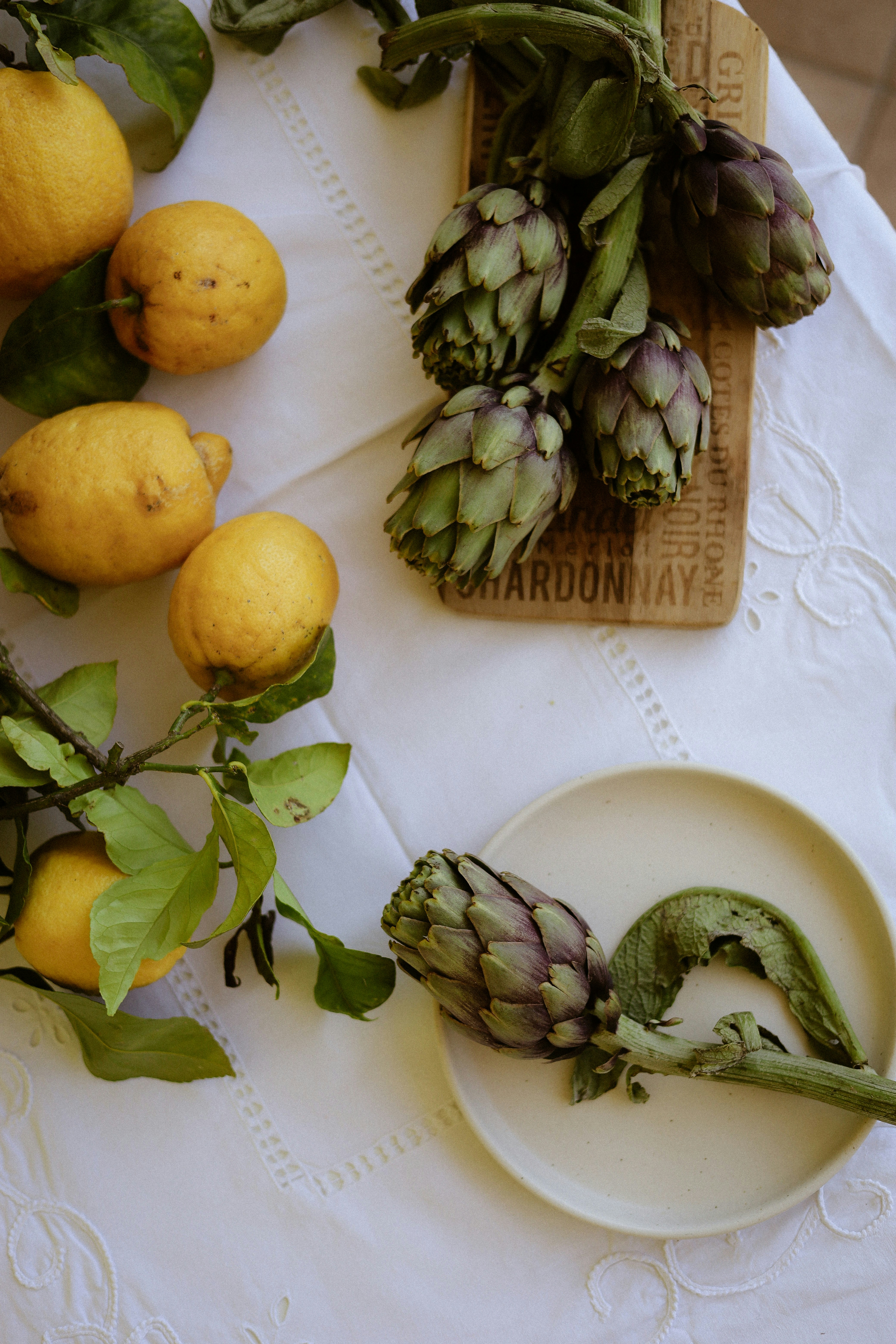 Lemons and artichokes on a white tablecloth
