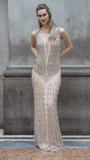 A woman poses in an embellished formal dress.