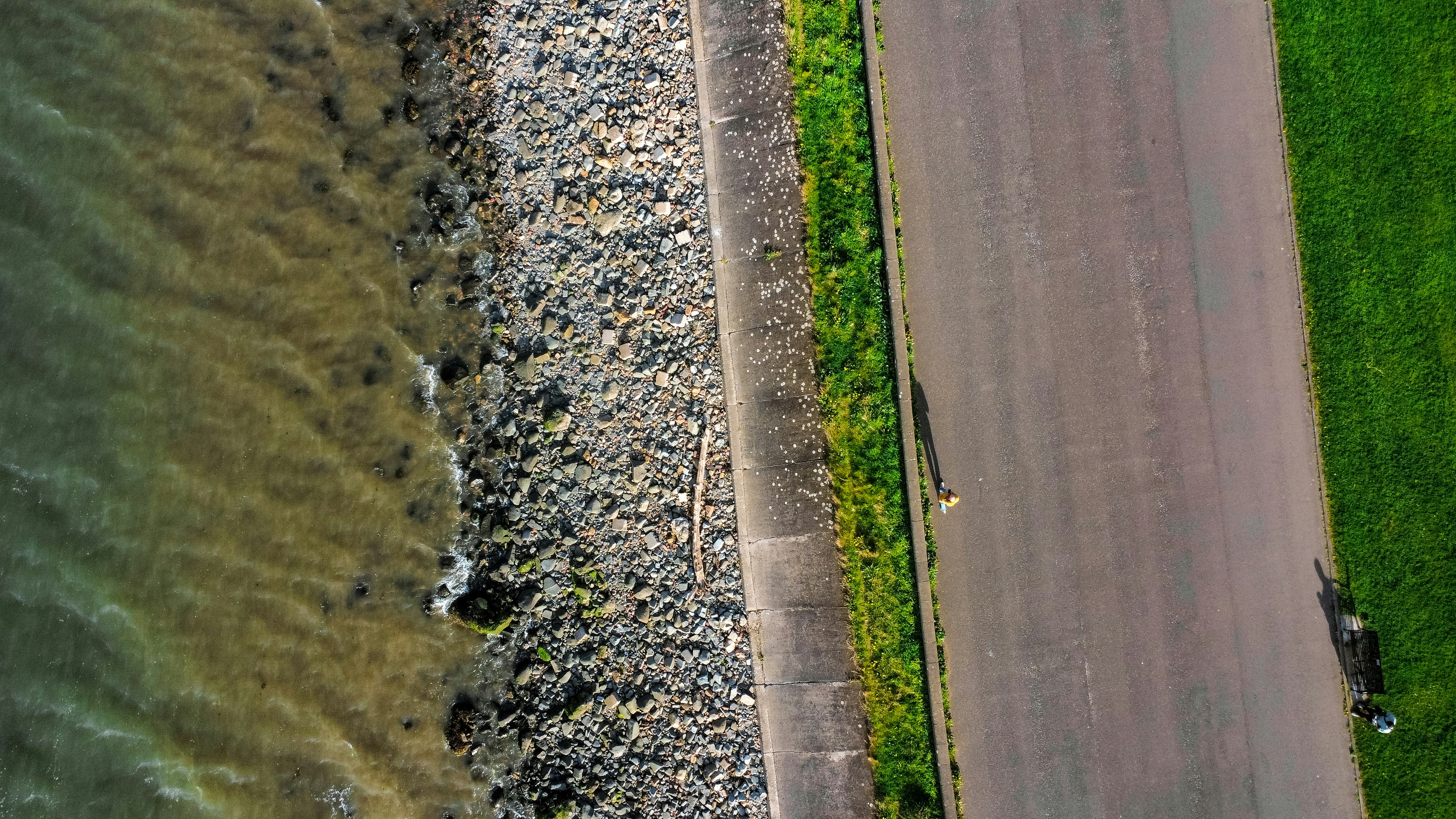An aerial shot showing water, rocks, and road.