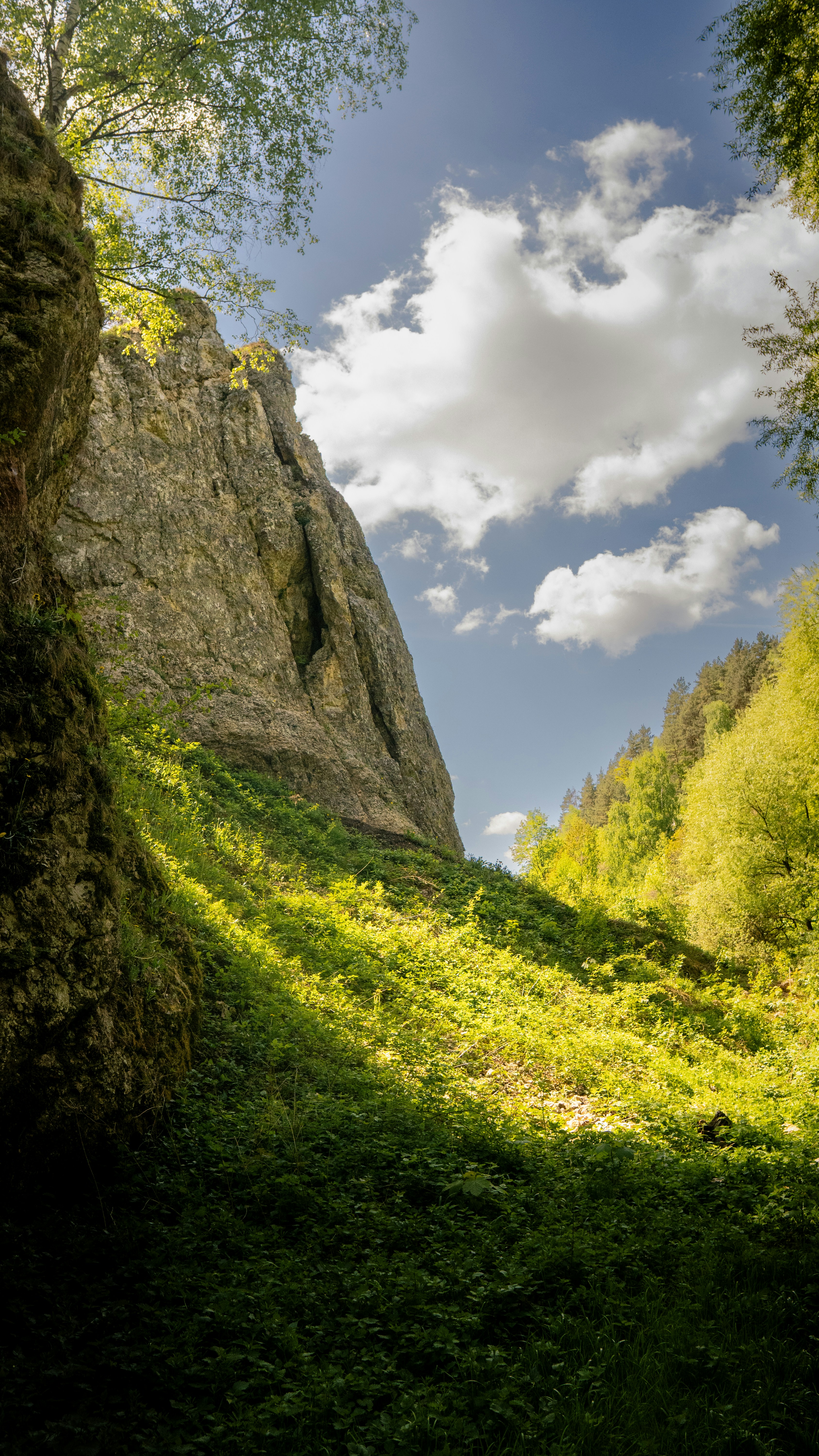 Sunlight illuminates a green valley between rocky cliffs.