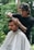 A barber is cutting a customer's hair outside.