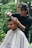 A barber is cutting a customer's hair outside.