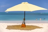 A yellow umbrella provides shade on the beach.