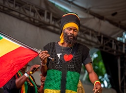 A rastafarian musician holds a flag on stage.