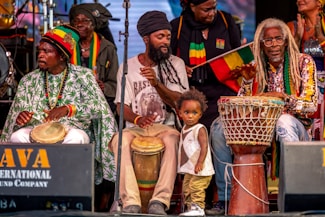 Musicians perform reggae music on stage with a child.