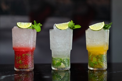 Three refreshing cocktails, garnished with limes and mint.