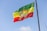 An ethiopian flag is waving in the sky.