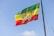 An ethiopian flag is waving in the sky.