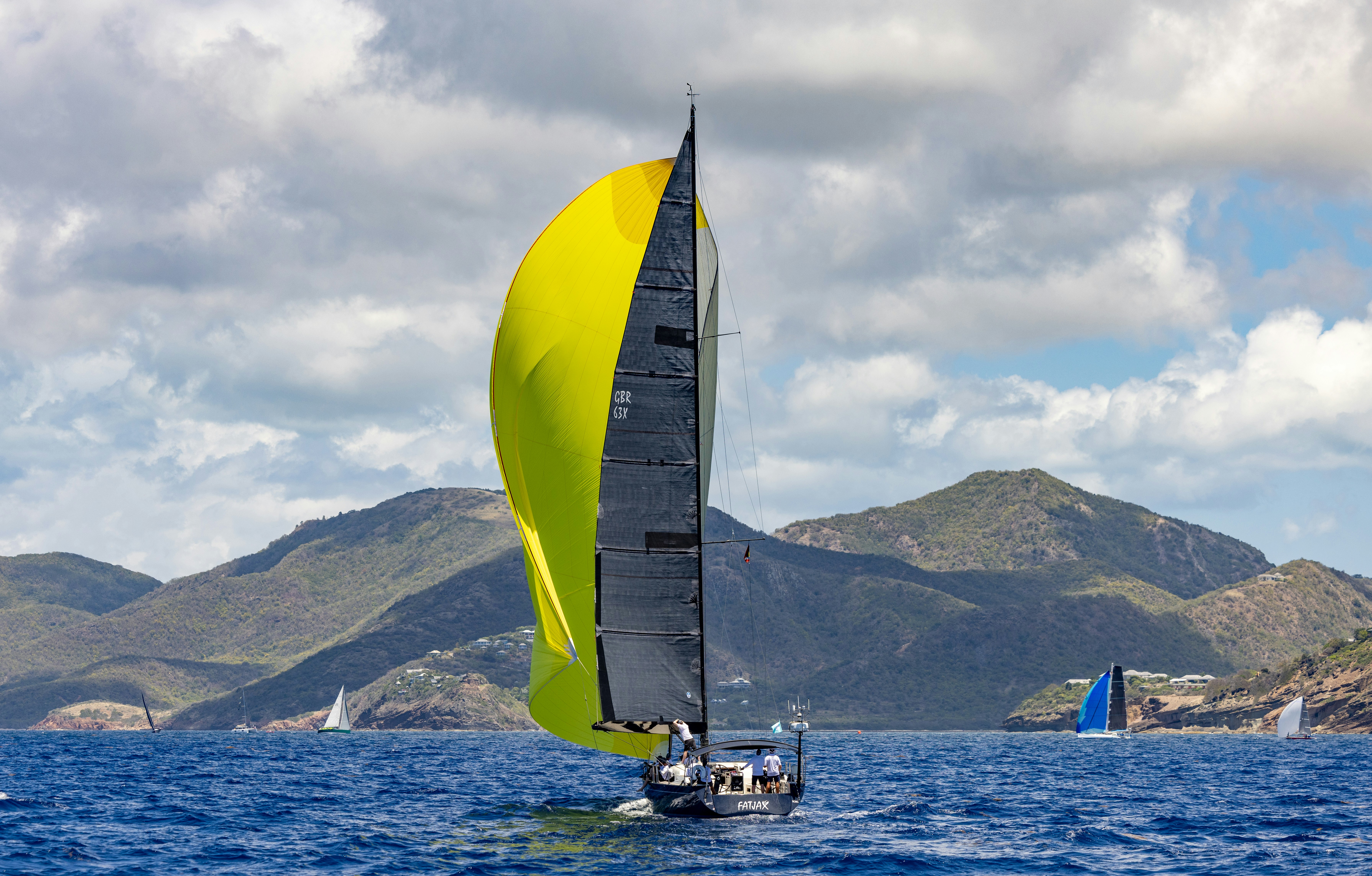 A sailboat sails through water with mountains in background.