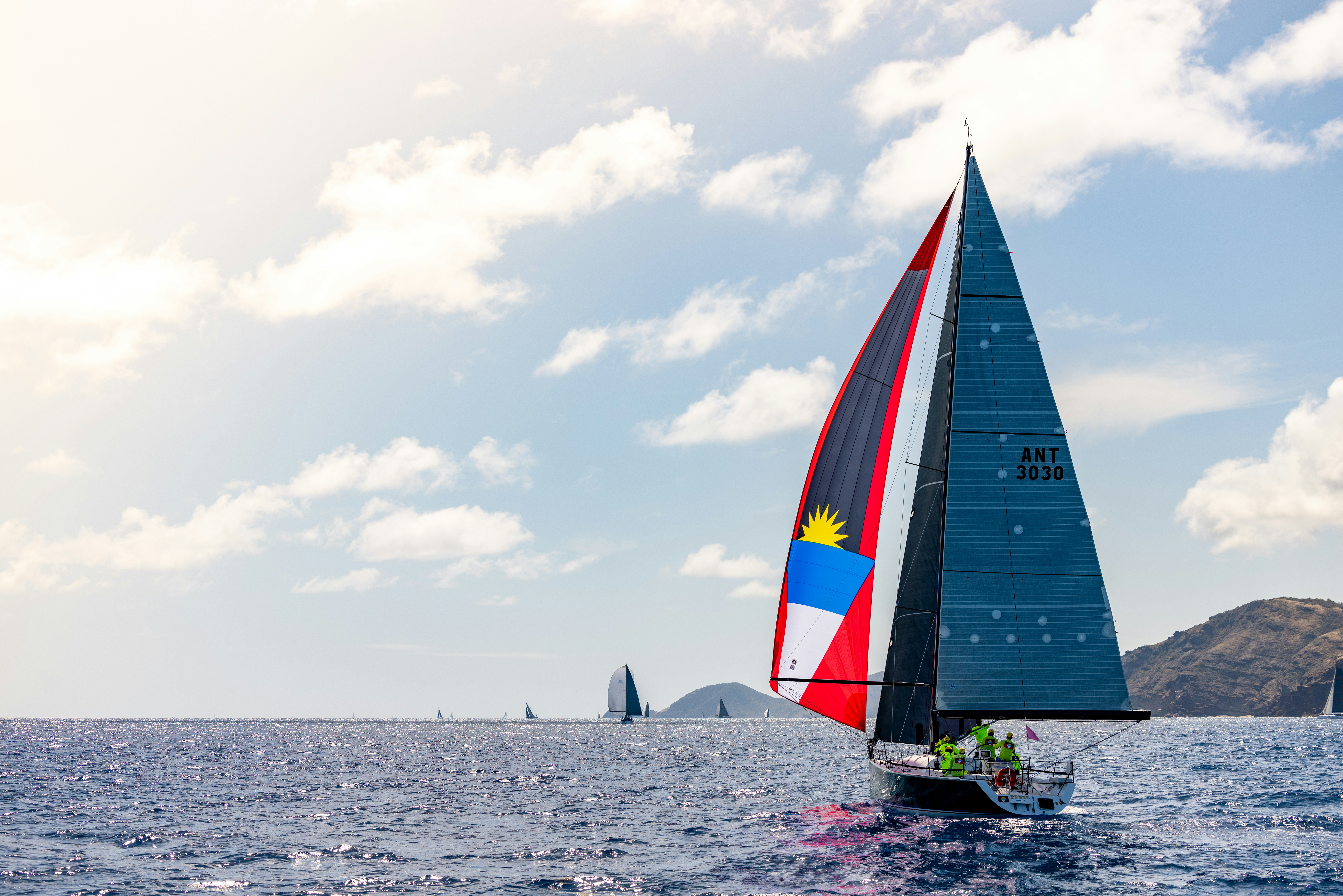 A sailboat races across the ocean under a blue sky.