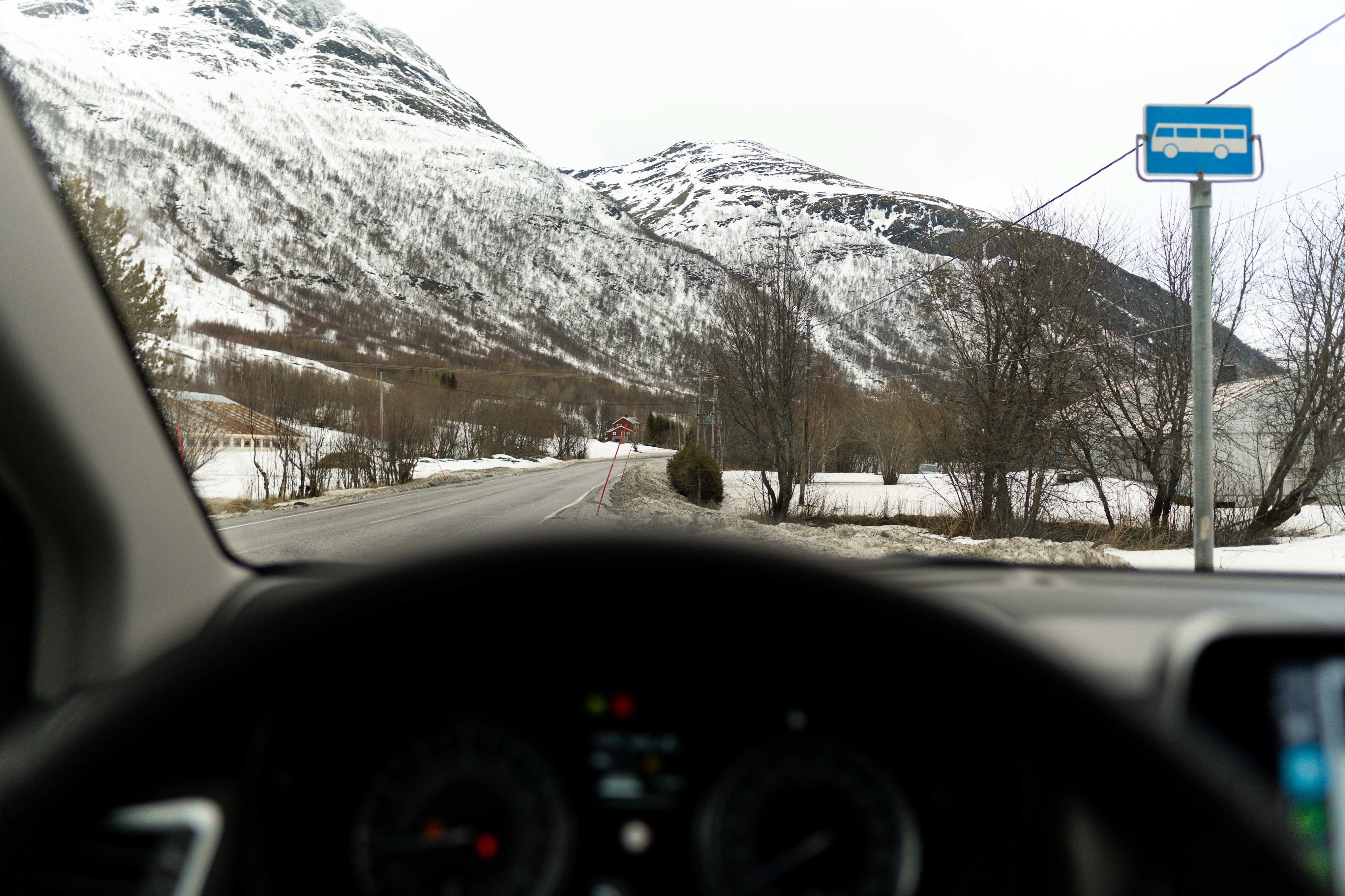 Driving toward snow-covered mountains on a road.