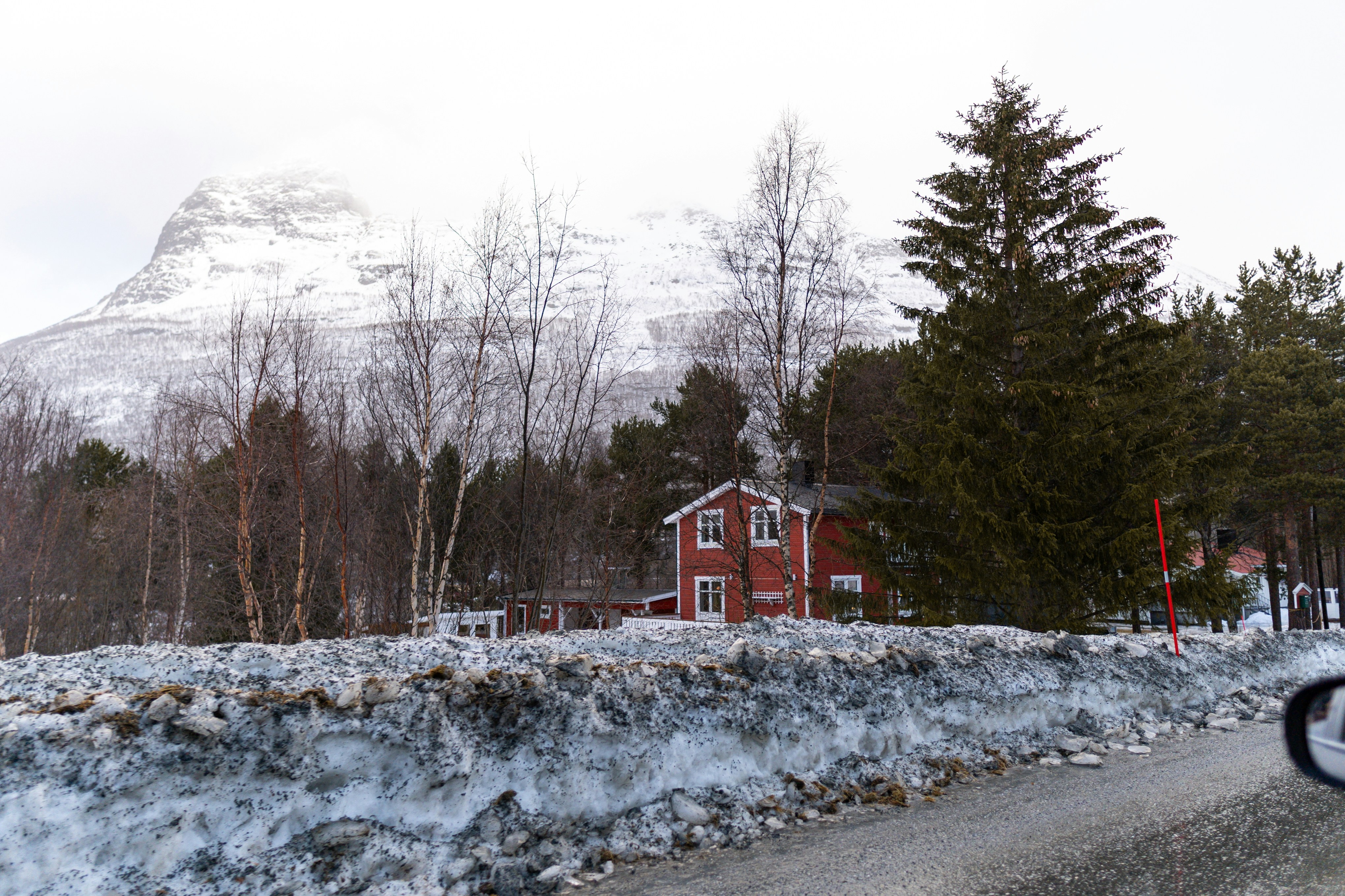 A red house sits before a snowy mountain.