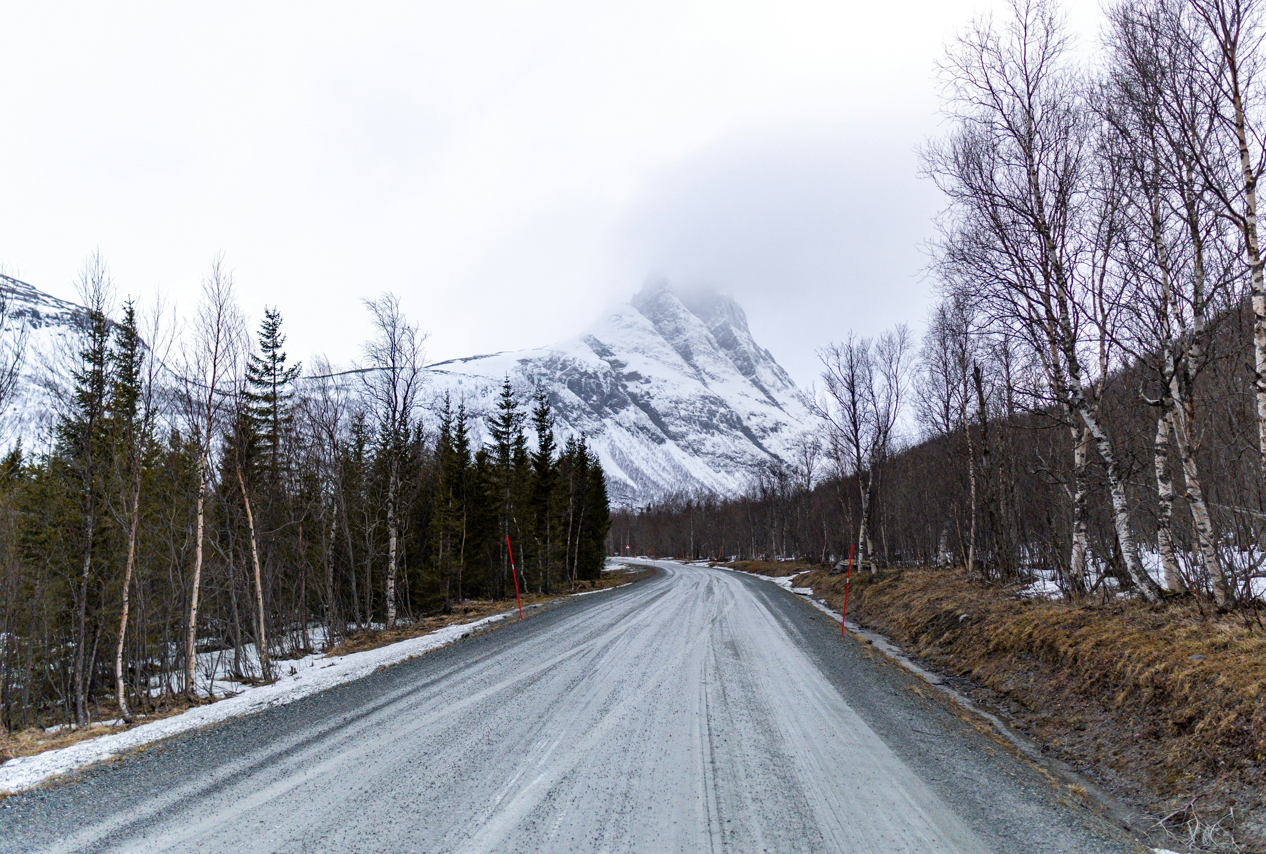 A snowy road leads towards a mountain.
