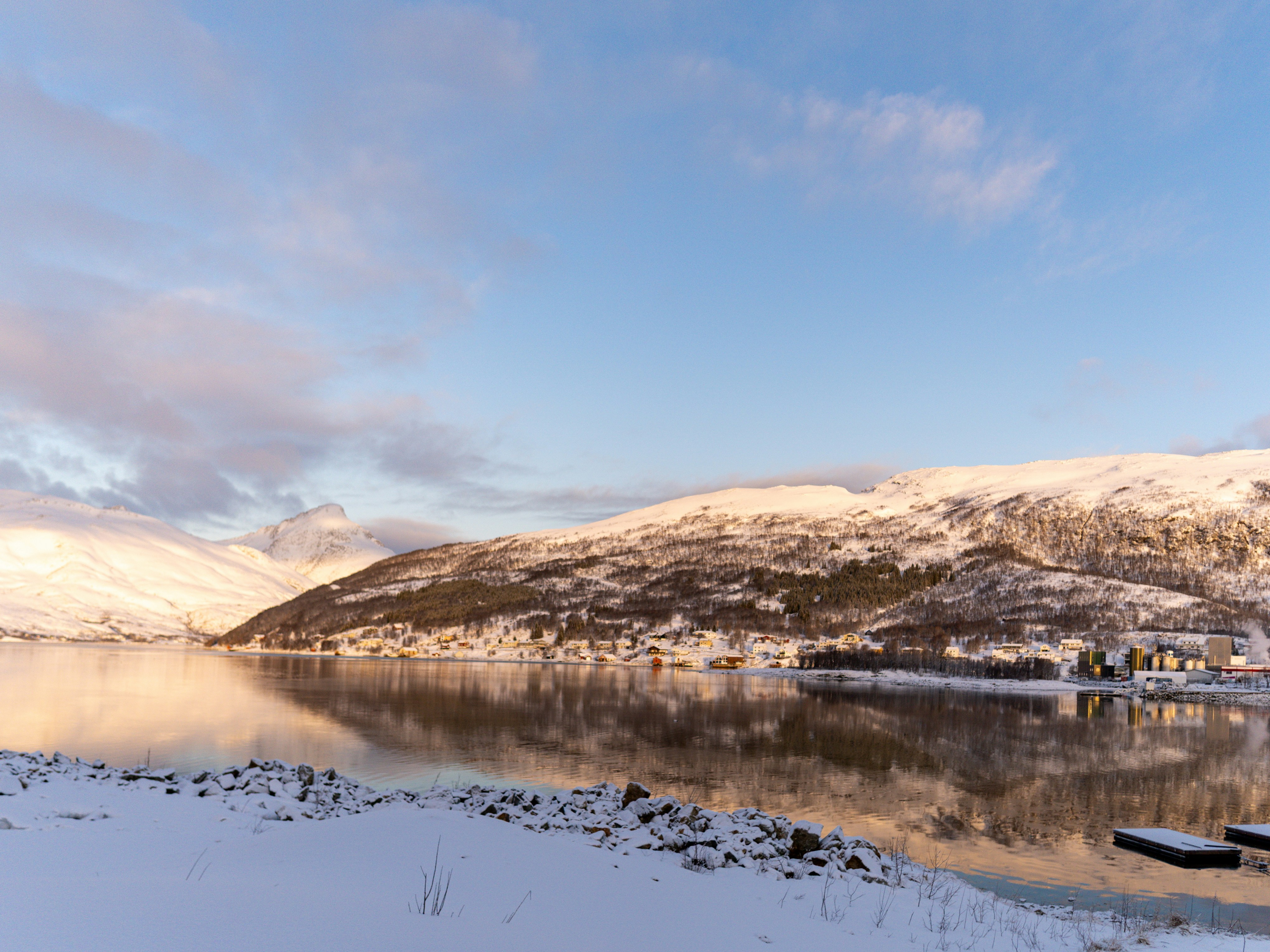 Snow-capped mountains reflect in the calm water.