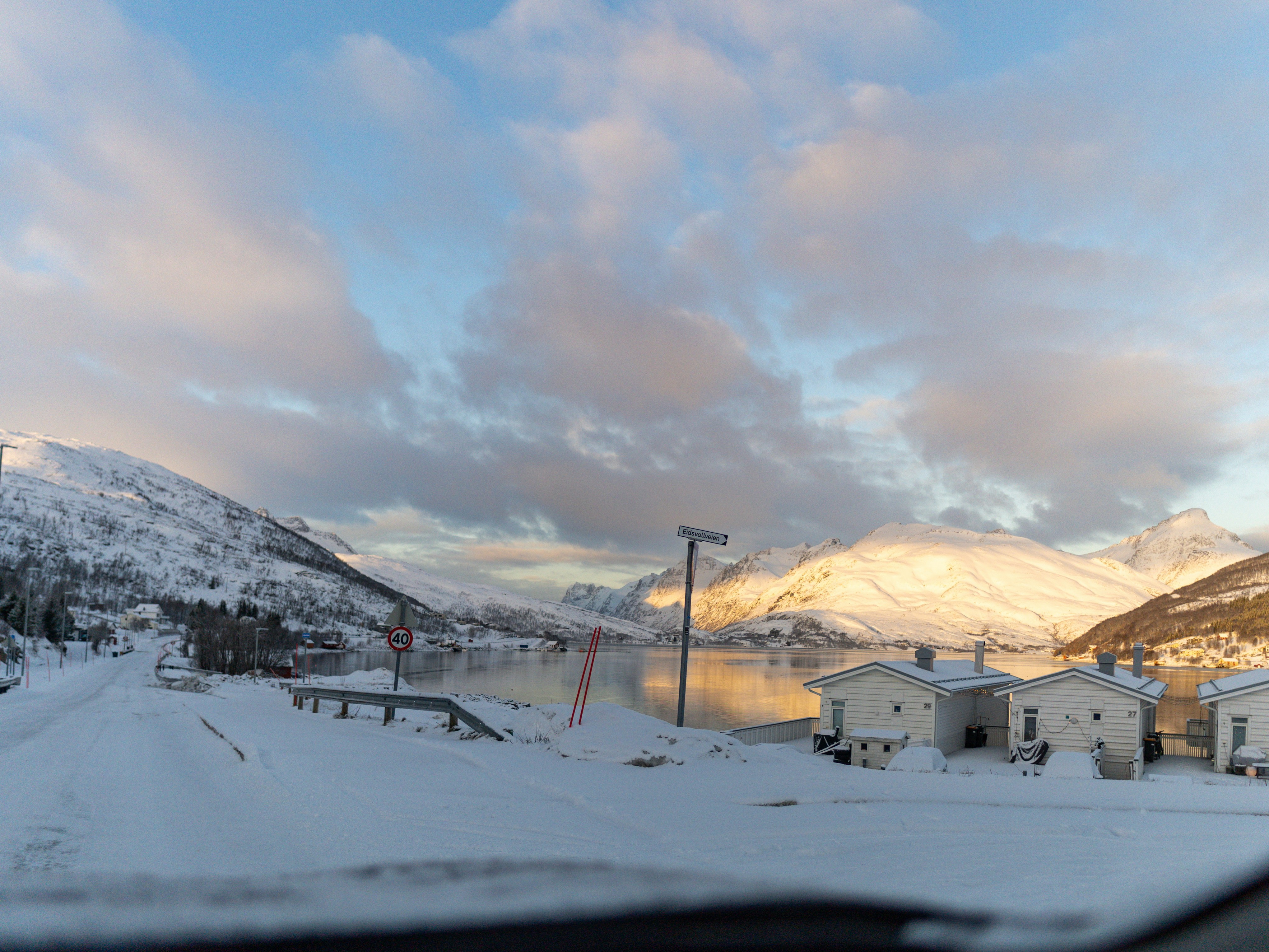 Snowy mountains and houses meet a beautiful sky.