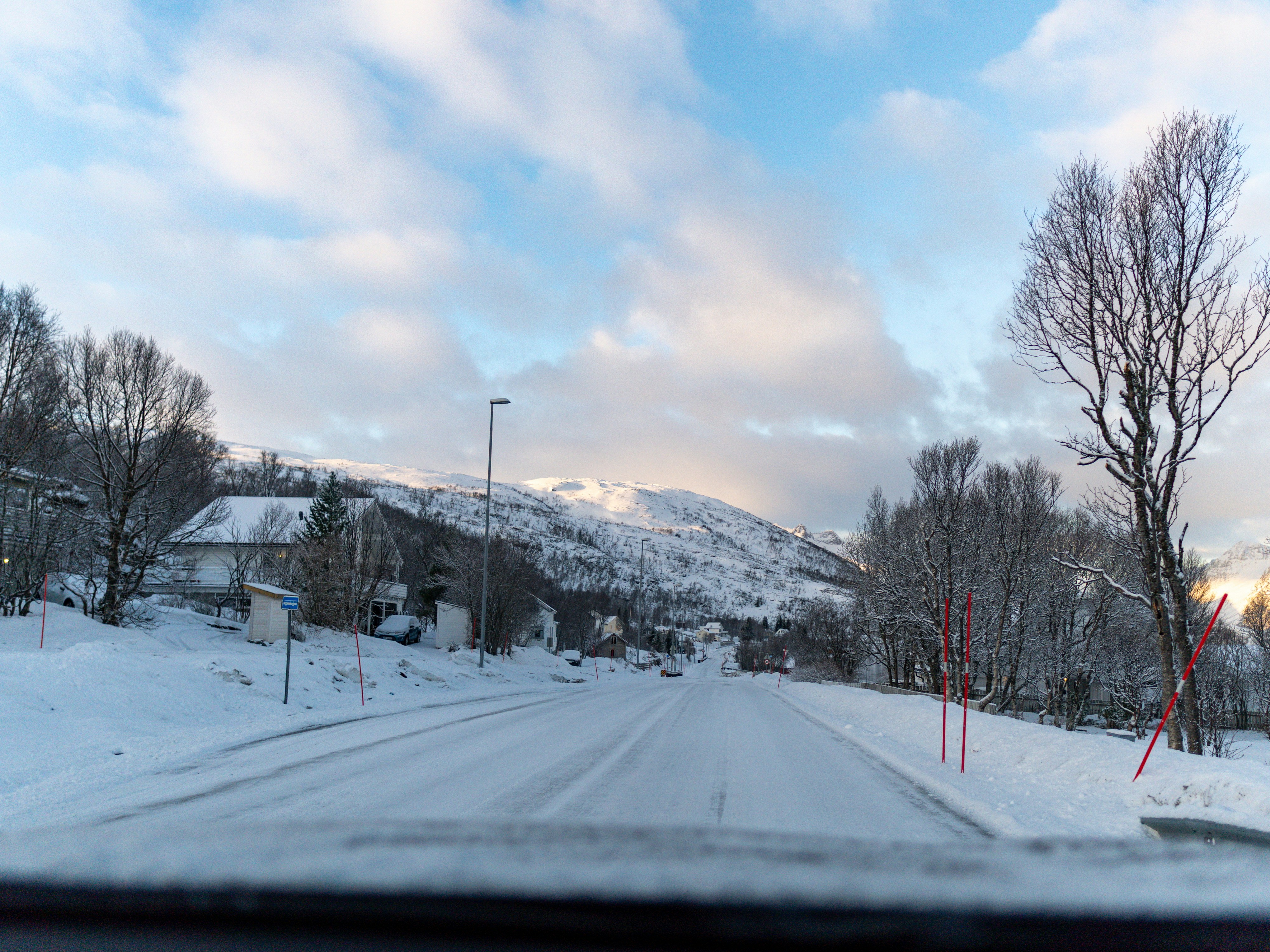 A snowy road leads to a mountain view.