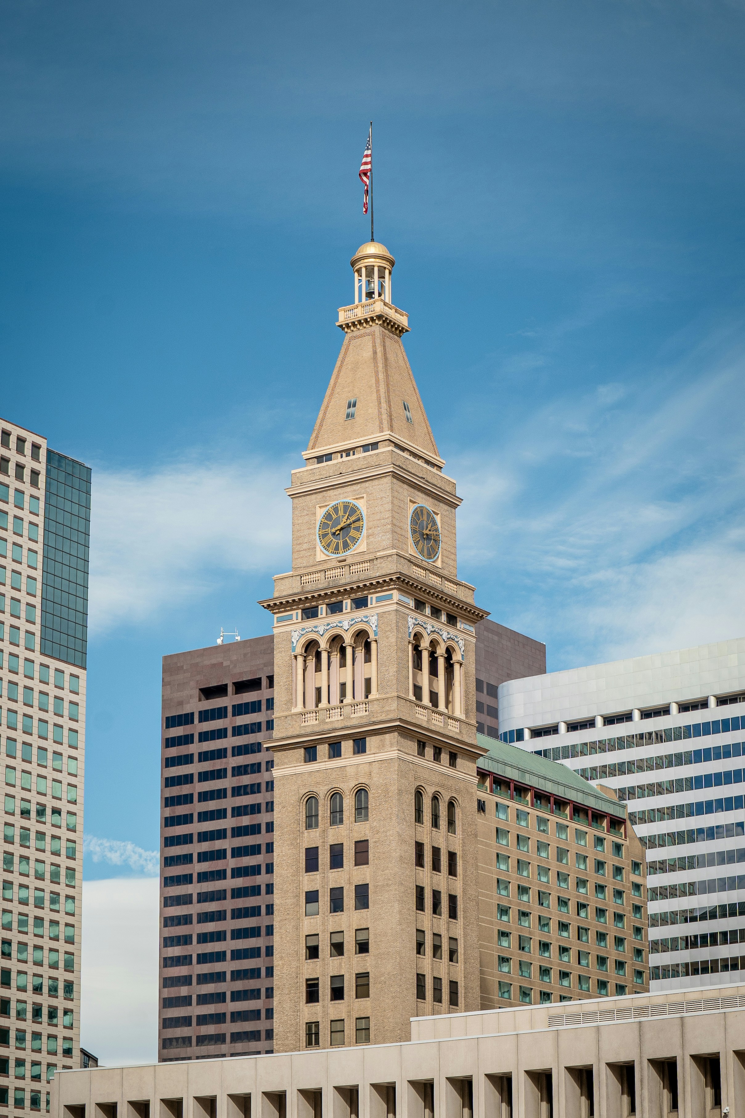 A tall building with a clock and flag.