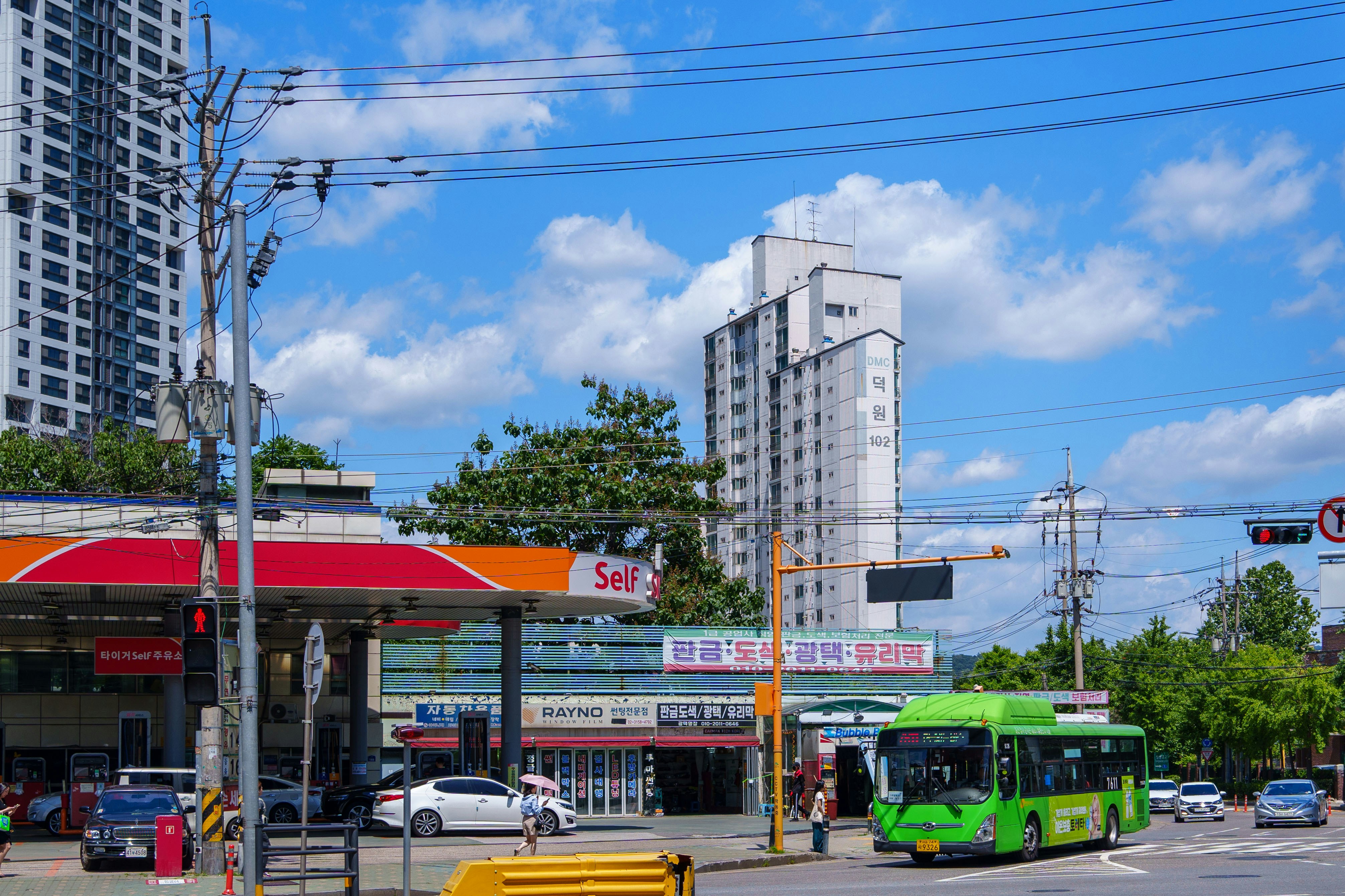 Cityscape featuring a gas station, bus, and buildings.