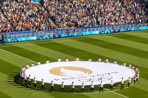 People hold the olympic flag on a field.