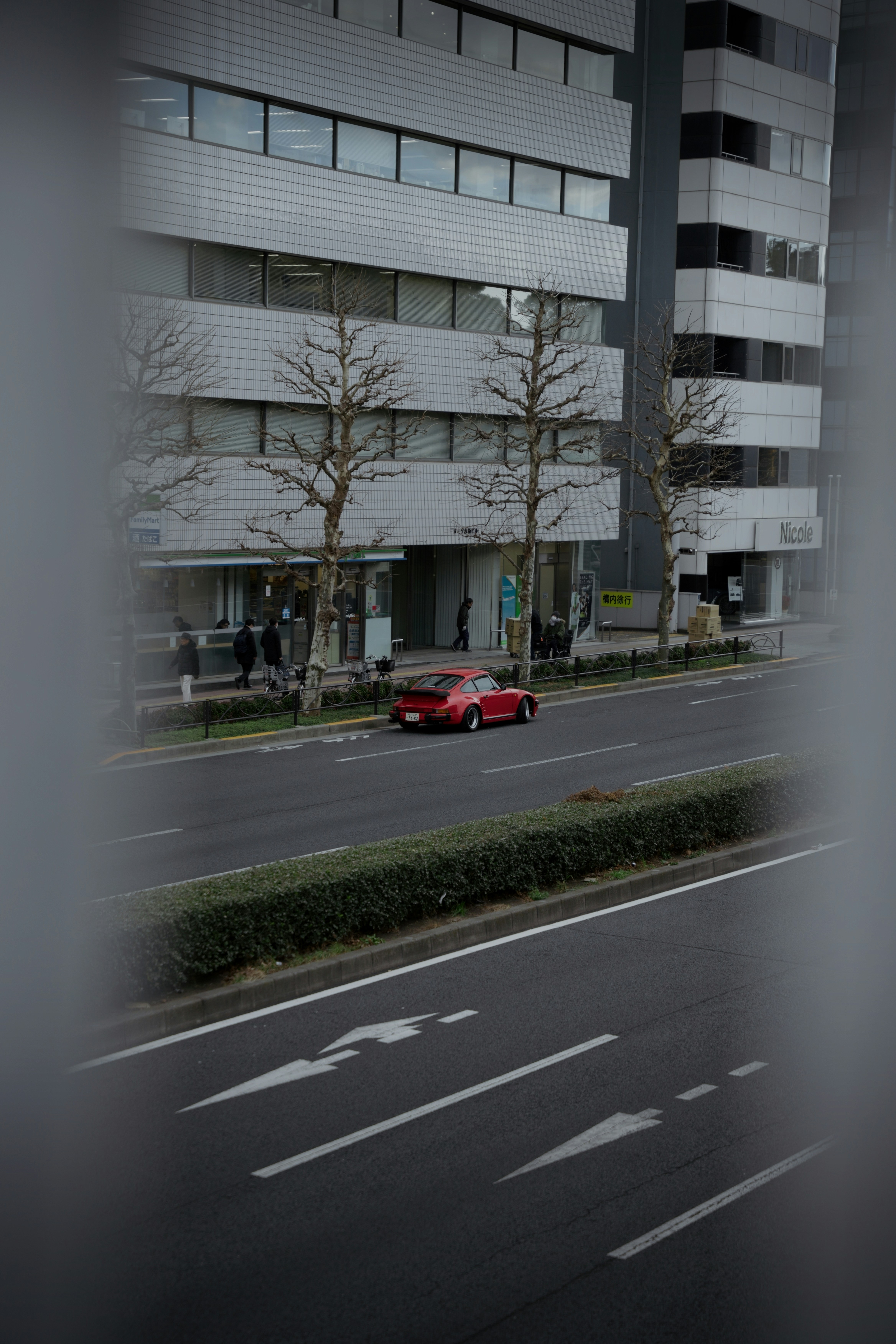 A red car drives down a city street.