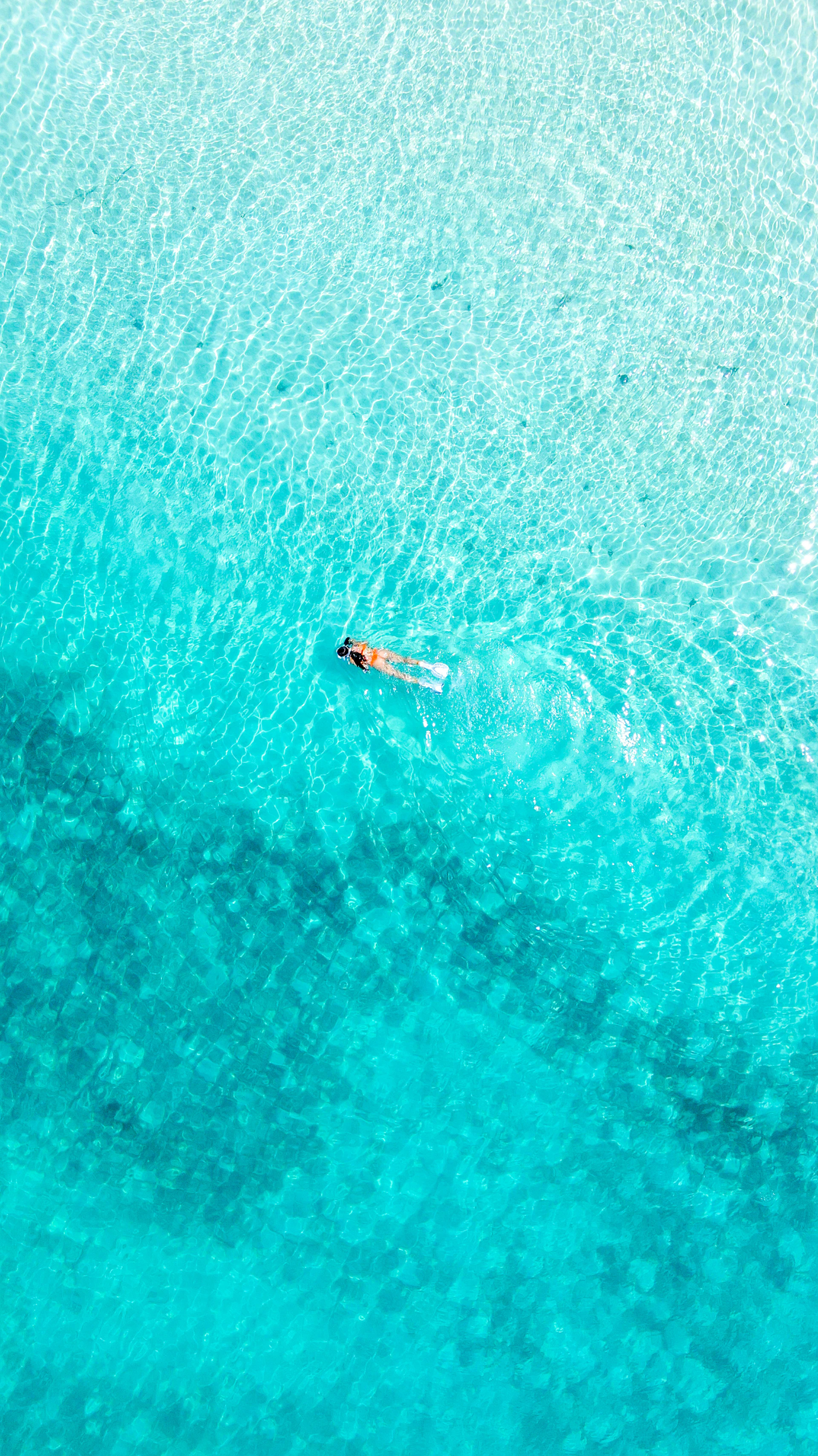 Someone is floating in clear blue water.
