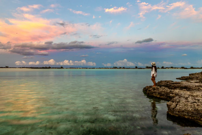 Sunset over calm water from a rocky shore in the Exumas