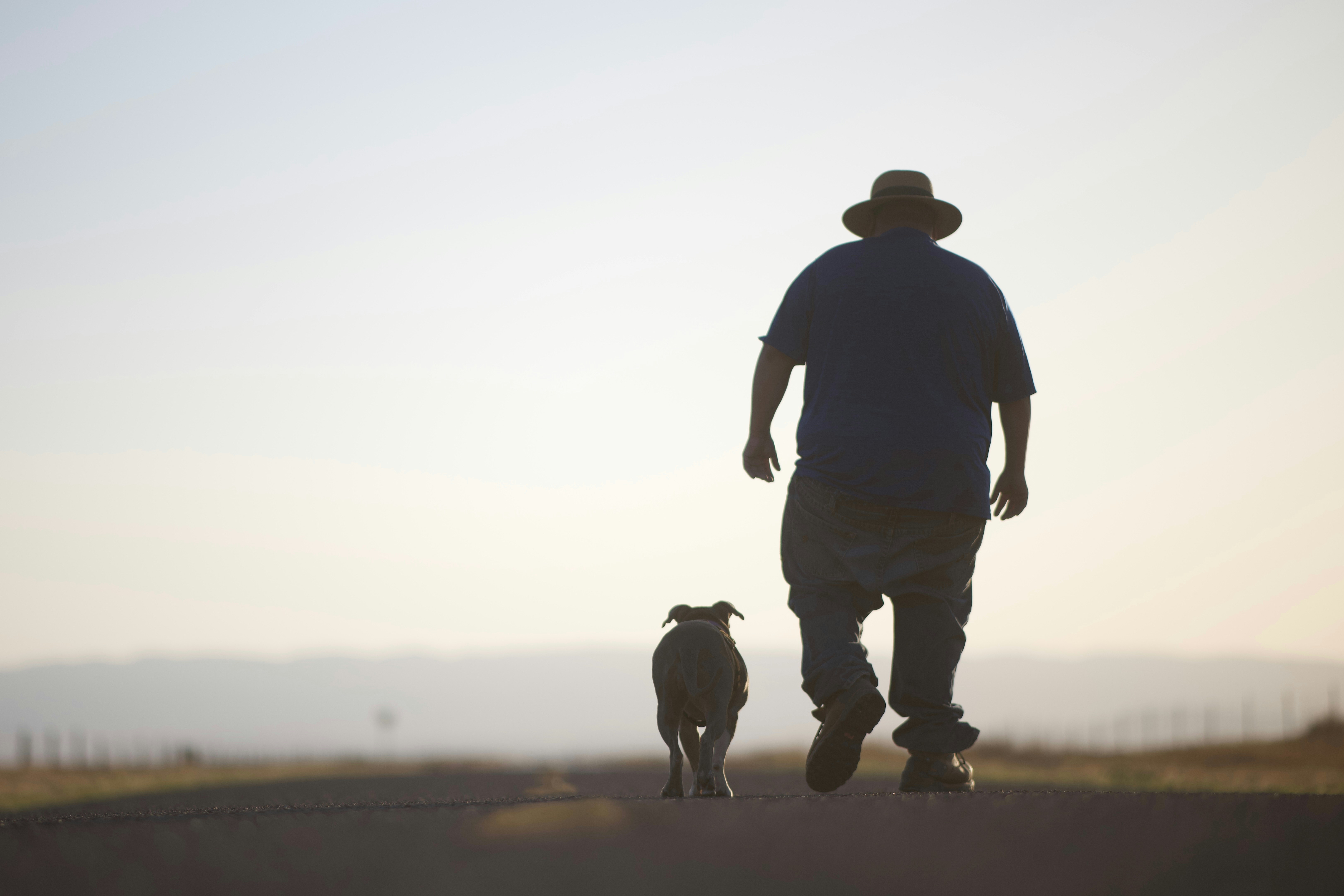 A man walks with his dog outdoors.