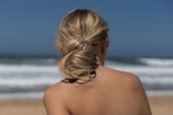 Woman with hair bun, overlooking the ocean.