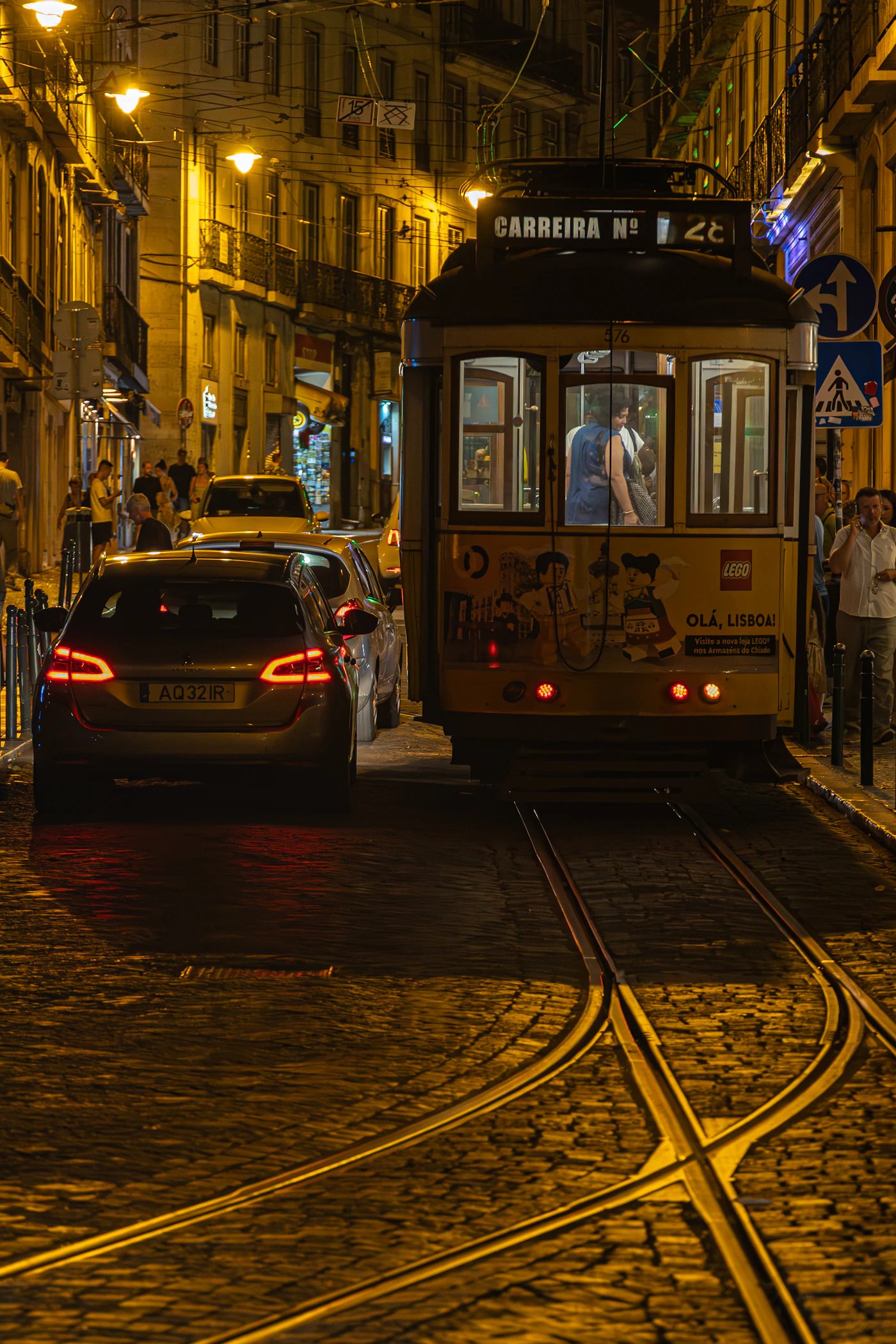 A yellow tram on a cobblestone street in Lisbon at night