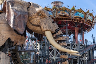 A giant elephant sculpture stands near a carousel.