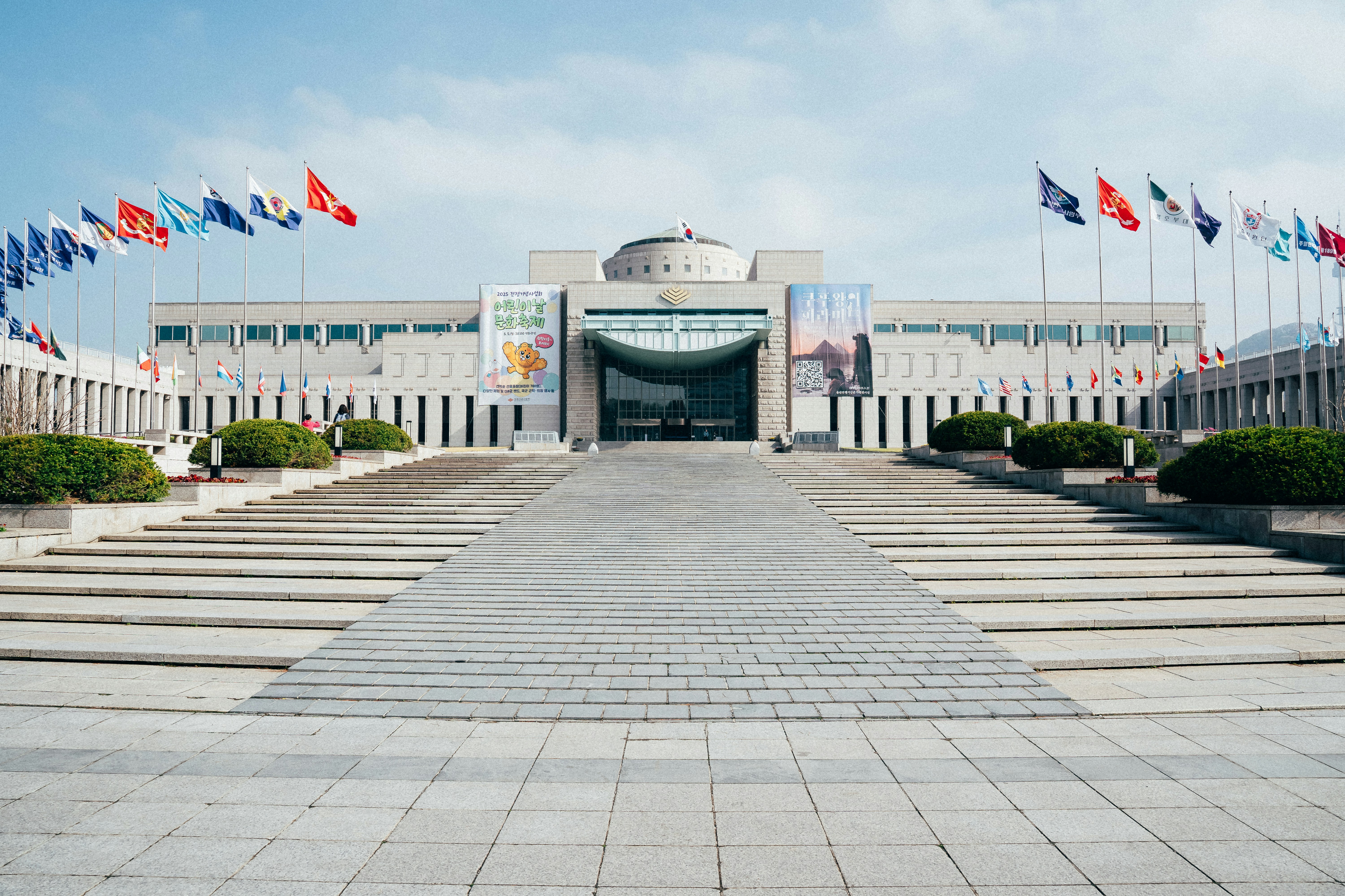 A grand building and pathway with flags.