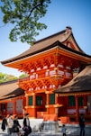 An orange japanese temple stands in the sunlight.