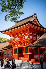 An orange japanese temple stands in the sunlight.