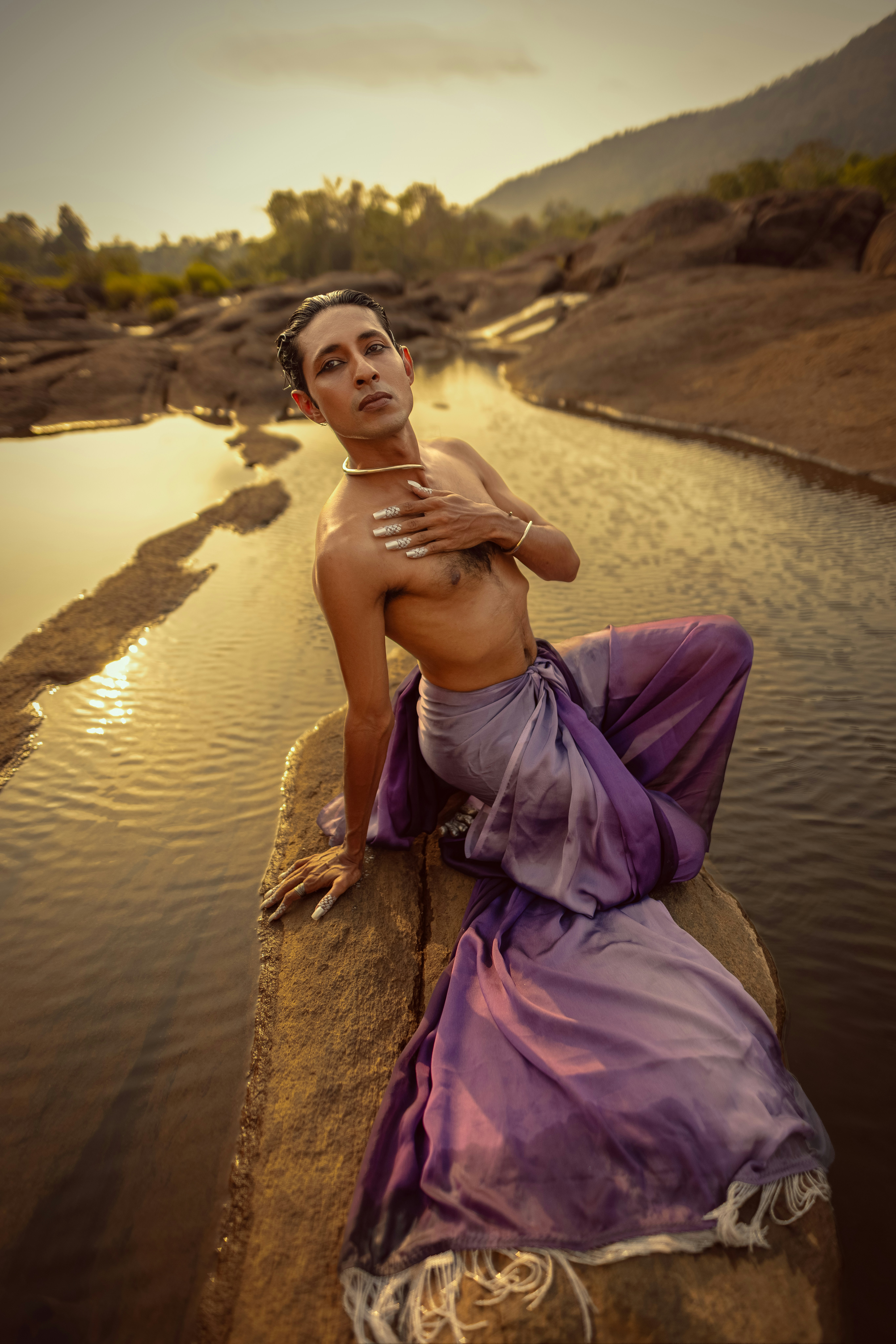A person poses by the water in gorgeous clothing.