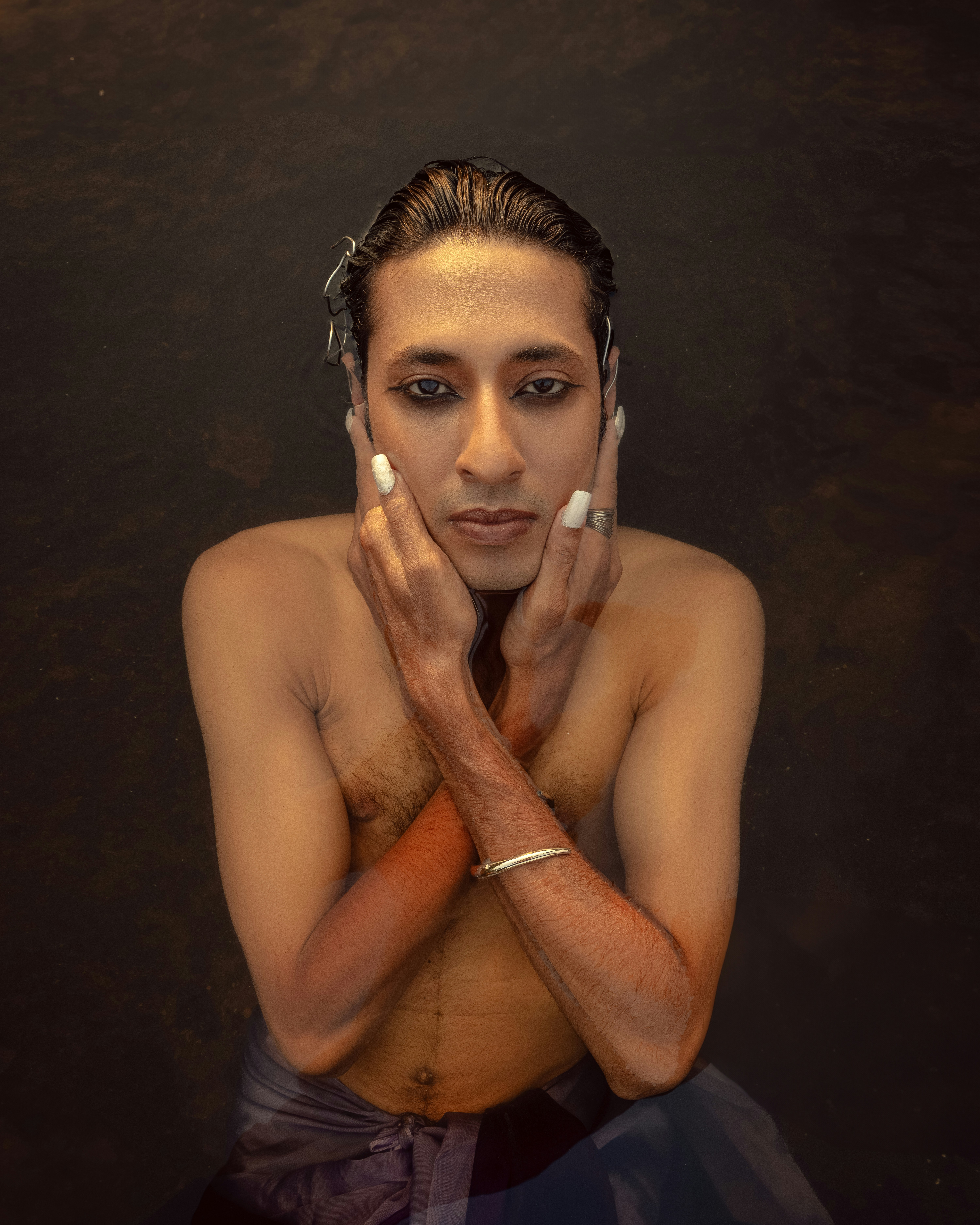 A man stares with his hands on his face.