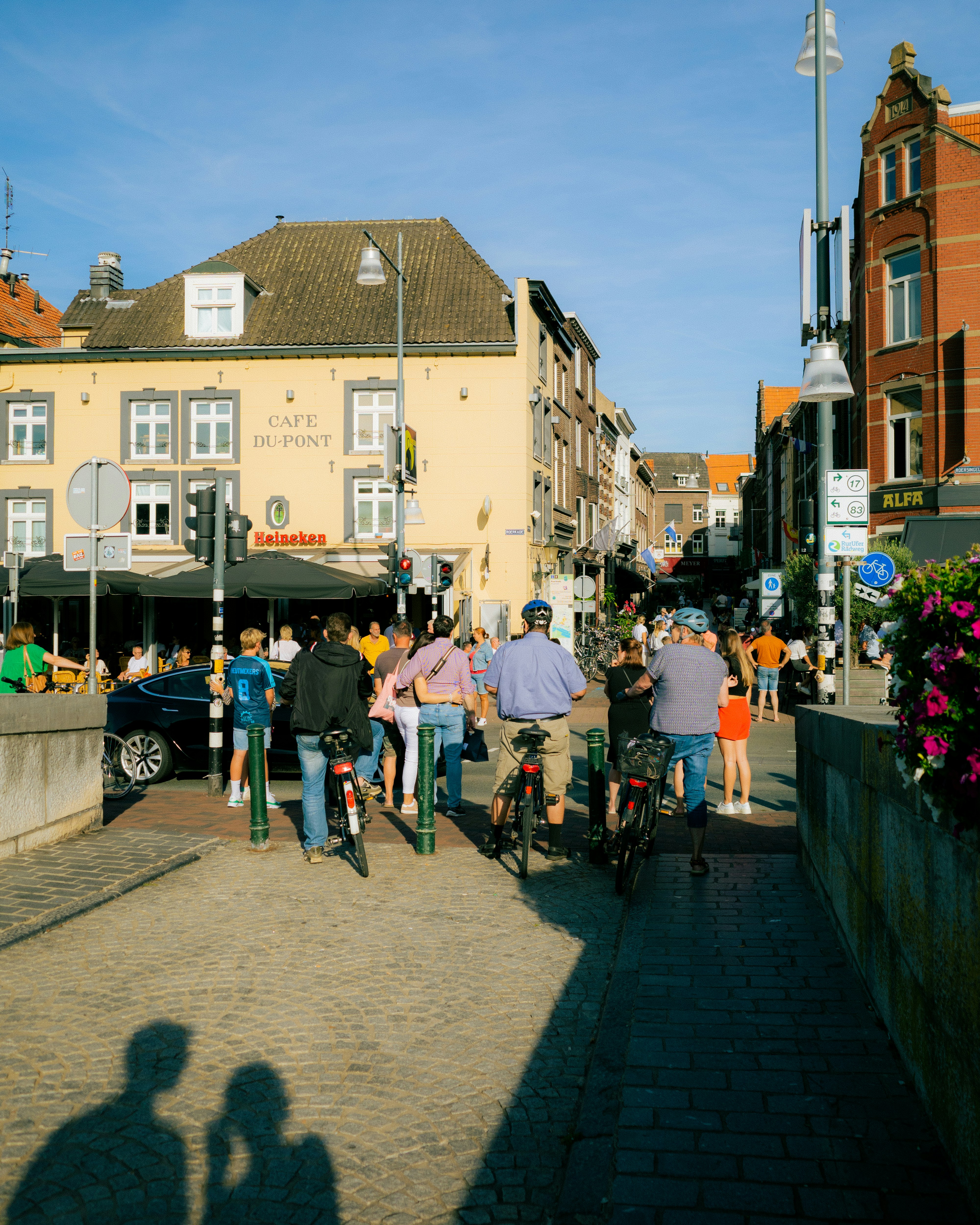 People walk and bike on a sunny street.