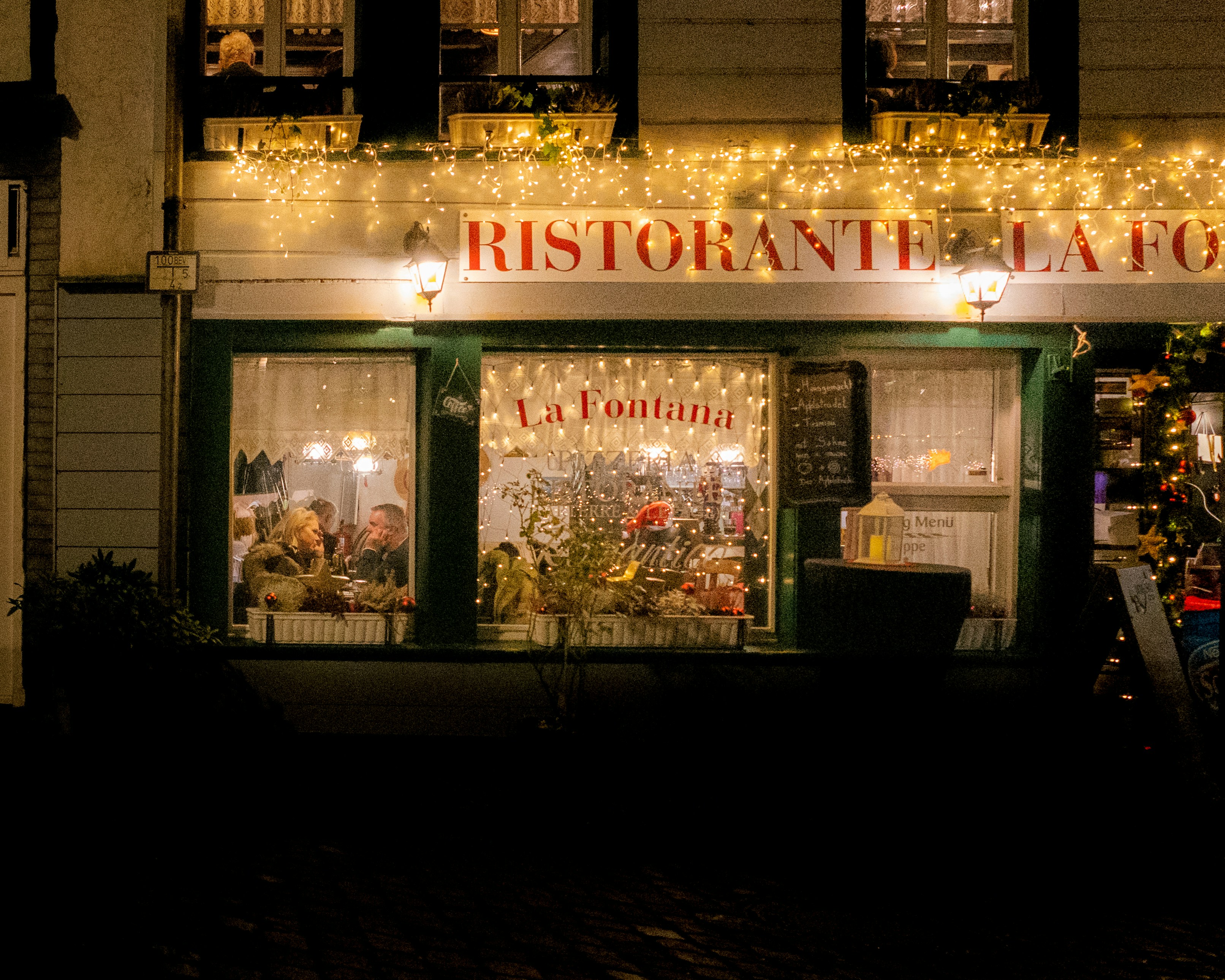 A cozy restaurant is decorated with christmas lights.