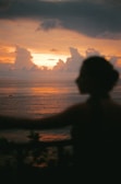 Sunset over the ocean with a person in silhouette.
