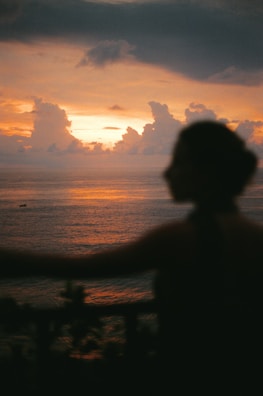 Sunset over the ocean with a person in silhouette.